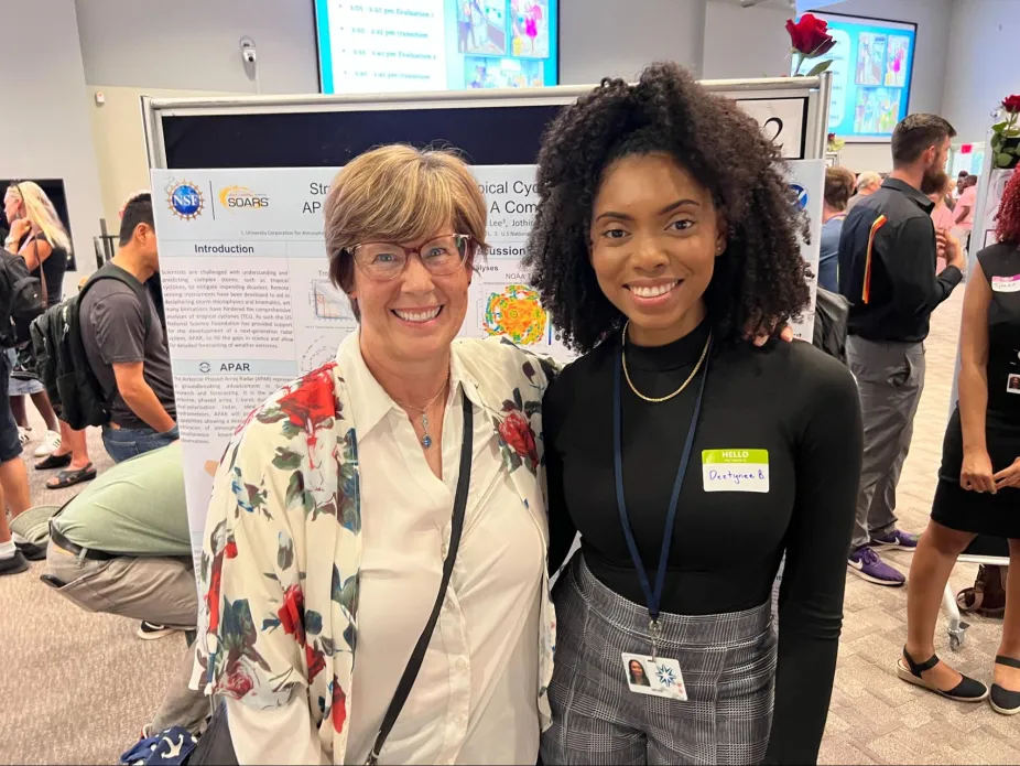 Two people posing for a photo at a poster session.