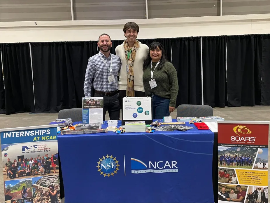 Three people standing at a professional NSF NCAR Booth