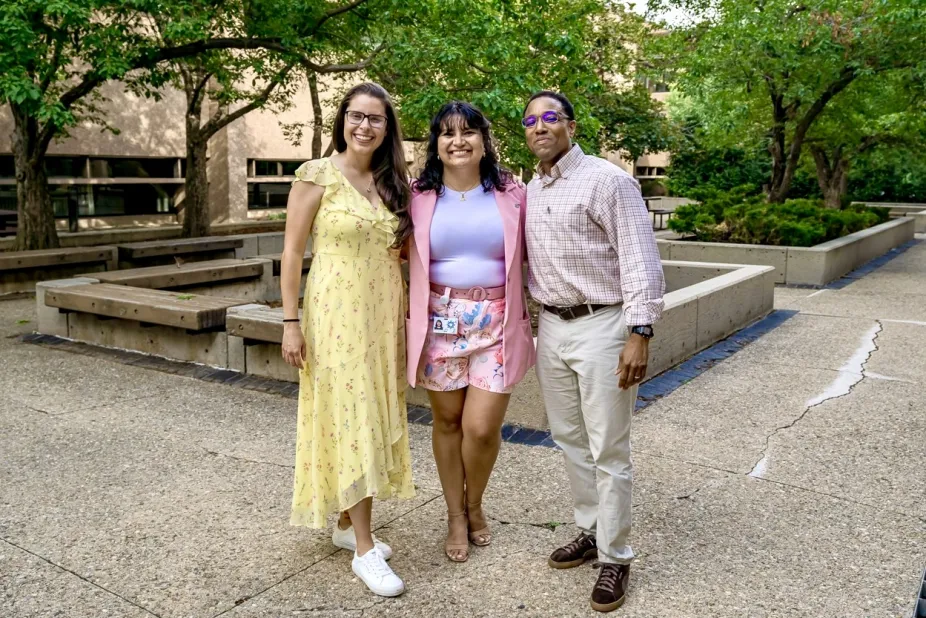 Three staff members posing and smiling at a camera