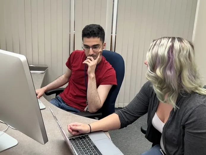 Two people work at a computer.